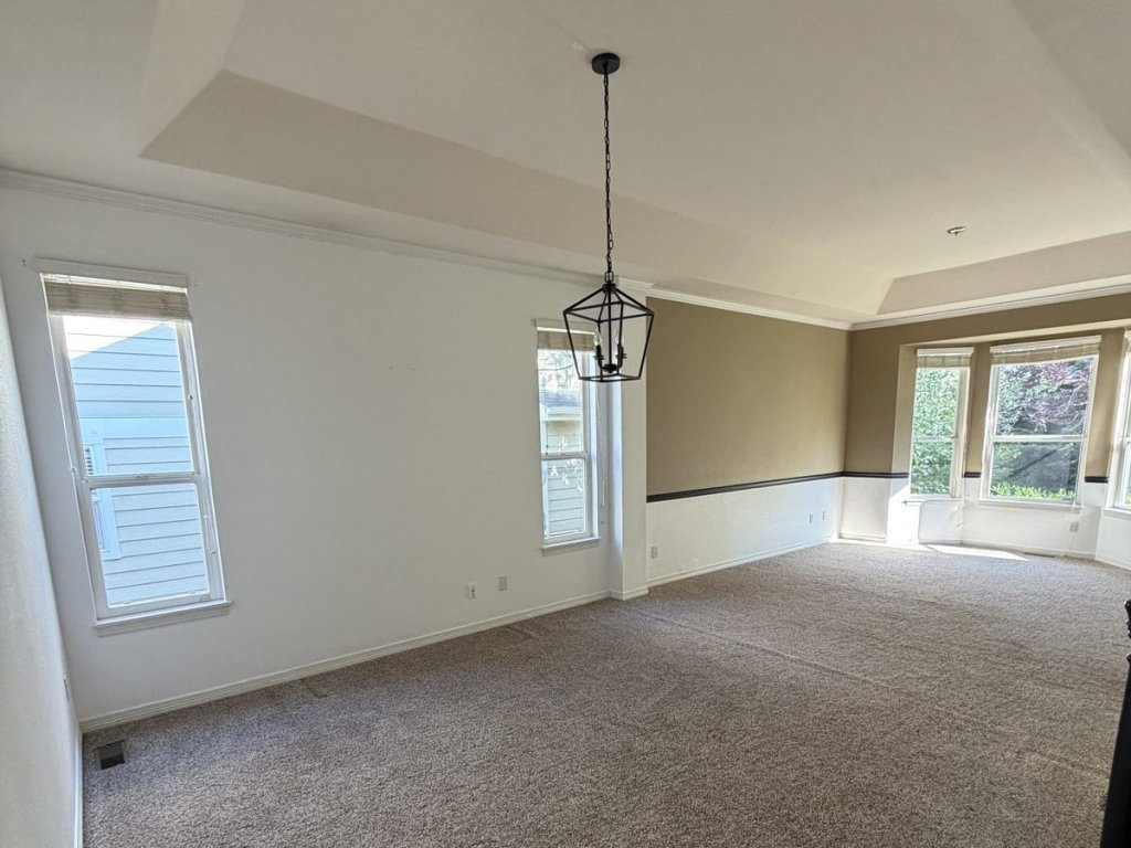 Living and dining room before the remodel in Highlands Ranch, with a tray ceiling, beige carpet, and two-tone painted walls